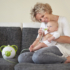 Immagine 8/11 - Anyuka a kanapén ülve kisgyermeke orrát szívja Nosiboo Pro2 elektromos orrszívóval