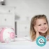Image 6/11 - Mosolygós kislány az ágyon könyököl, mellette Pink Nosiboo pro elektromos orrszívó